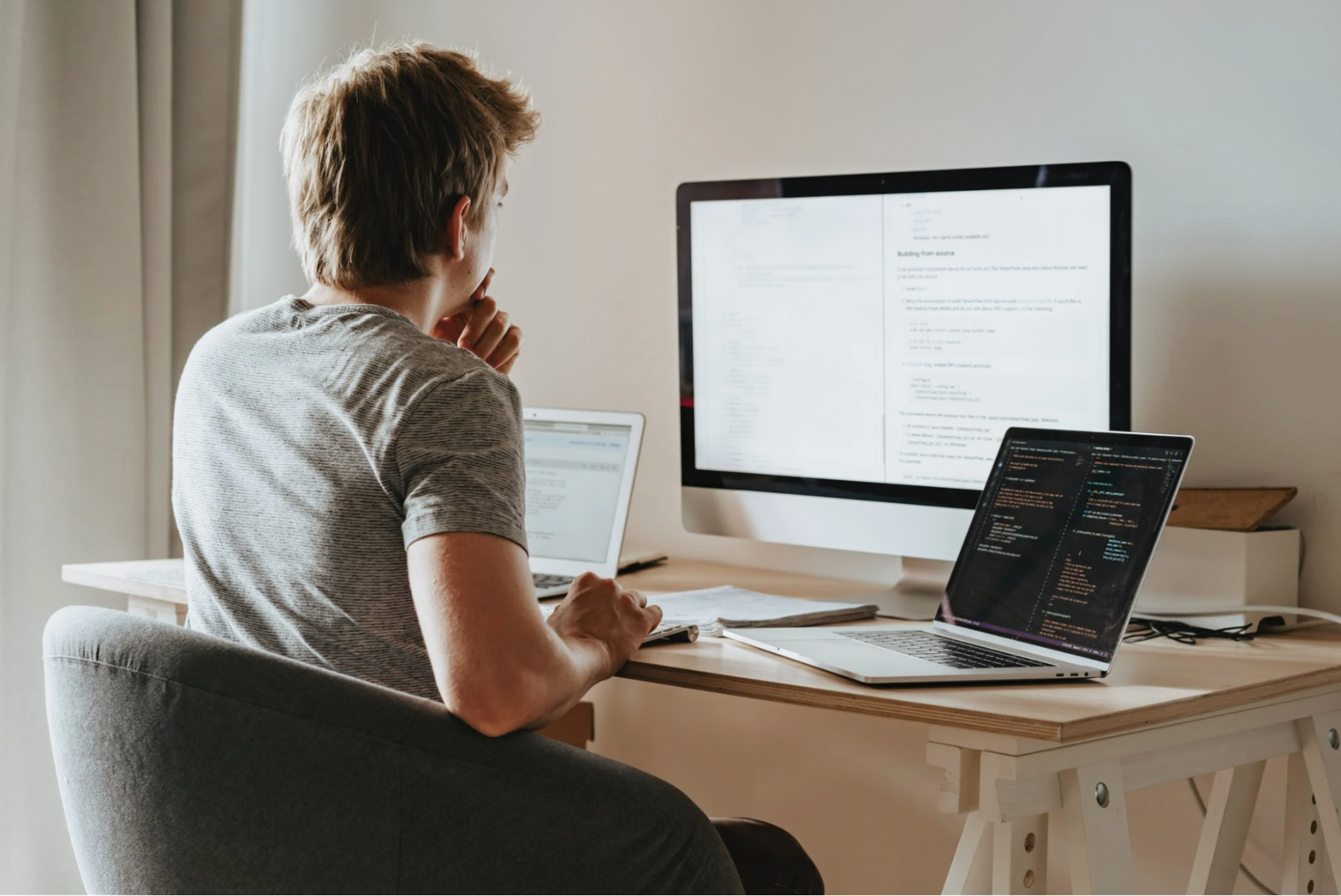 young man sitting behind the multiple screens working on Knowledge Management System