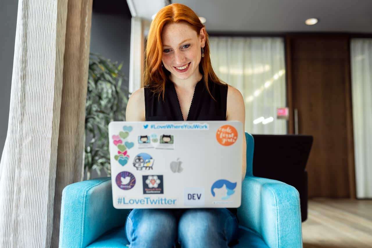 a red-haired woman sitting with a laptop on her lap