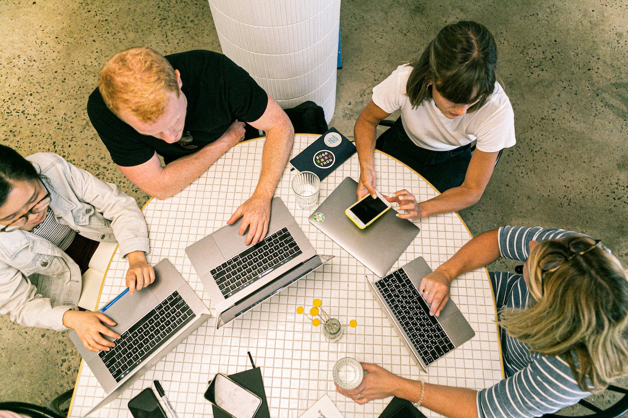a group of people with macbooks sitting at a desk