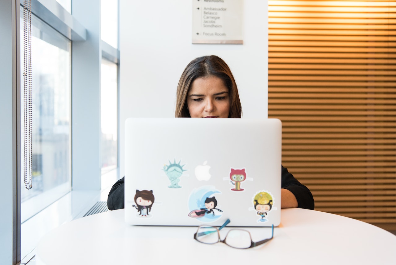 a woman sitting in front of a macbook