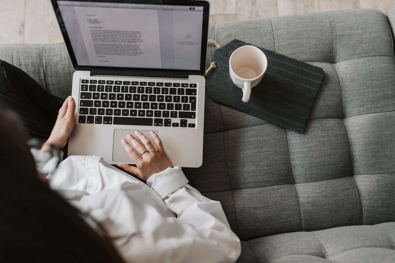 A woman sitting in front of a laptop at a couch